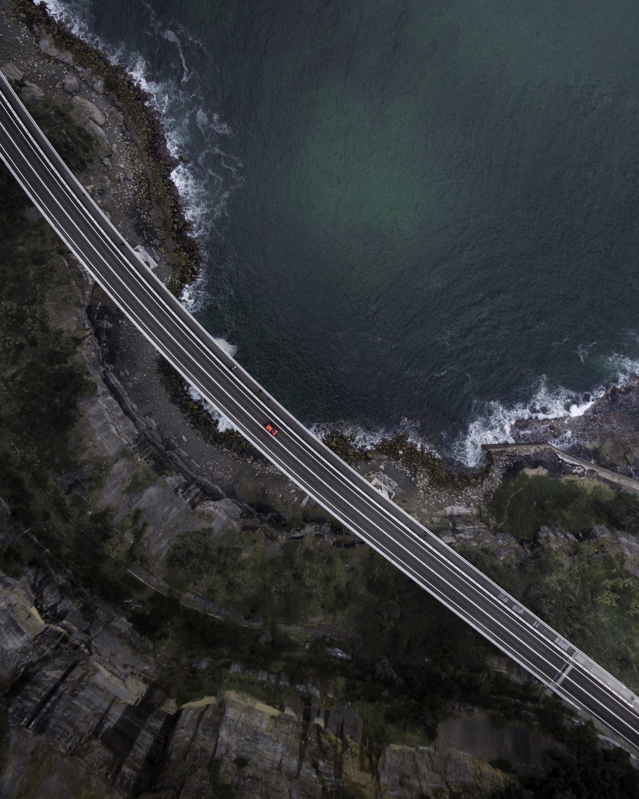 vista aérea de una carretera asfaltada recta con un coche circulando por la orilla del mar a escala